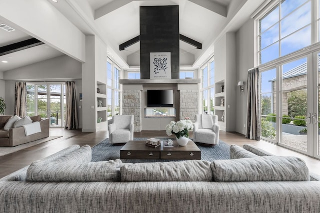 living room with beamed ceiling, a healthy amount of sunlight, and high vaulted ceiling