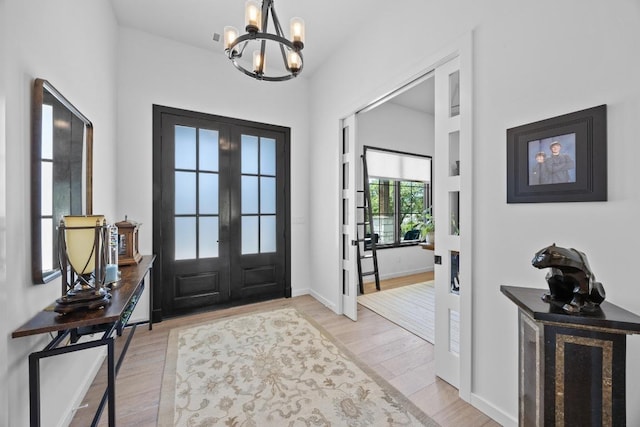 4010 County Road 404, Spicewood, TX 78669 - entrance foyer with french doors, a chandelier, light wood-style floors, and baseboards