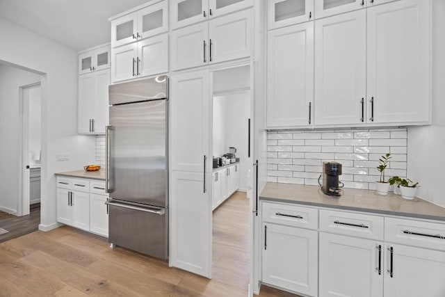 4010 County Road 404, Spicewood, TX 78669 - kitchen featuring built in fridge, light wood-style flooring, decorative backsplash, and white cabinetry