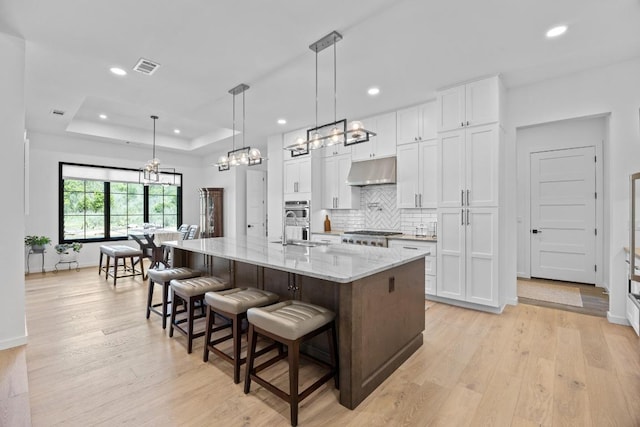 4010 County Road 404, Spicewood, TX 78669 - kitchen with a chandelier, under cabinet range hood, white cabinets, backsplash, and recessed lighting