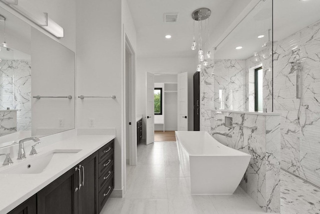 4010 County Road 404, Spicewood, TX 78669 - bathroom featuring a freestanding tub, vanity, recessed lighting, a marble finish shower, and tile walls