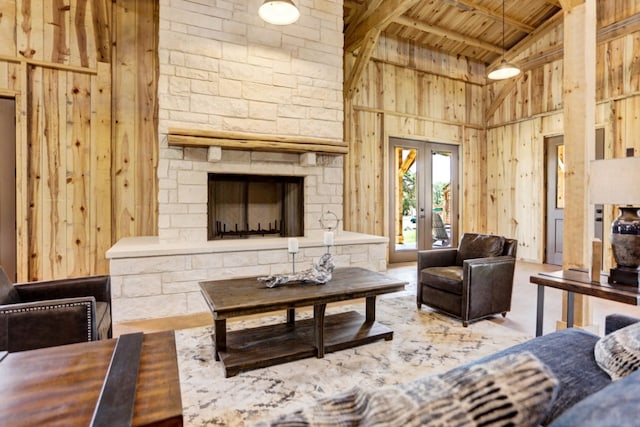 4010 County Road 404, Spicewood, TX 78669 - living area featuring wooden ceiling with exposed beams, a stone fireplace, high vaulted ceiling, wooden walls, and french doors