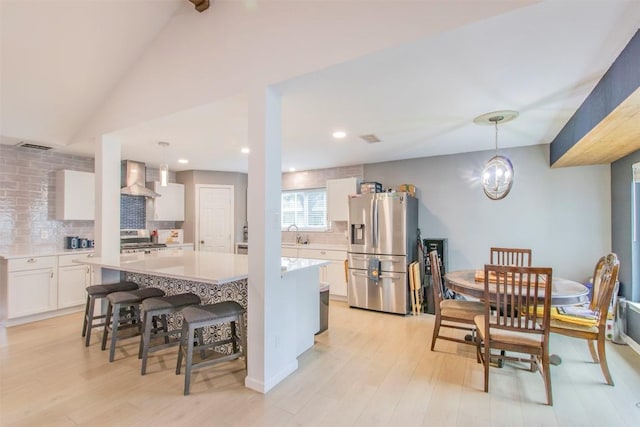 2400 Braemar Cv, Austin, TX 78747 - kitchen with stainless steel appliances, wall chimney exhaust hood, white cabinetry, decorative backsplash, and light countertops
