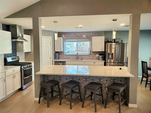 2400 Braemar Cv, Austin, TX 78747 - kitchen with appliances with stainless steel finishes, a breakfast bar area, light wood finished floors, and recessed lighting