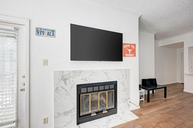 interior details with a premium fireplace, a textured ceiling, wood finished floors, and ornamental molding
