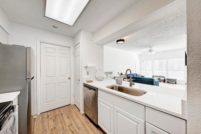kitchen featuring light wood-style flooring, light countertops, white cabinetry, appliances with stainless steel finishes, and a sink