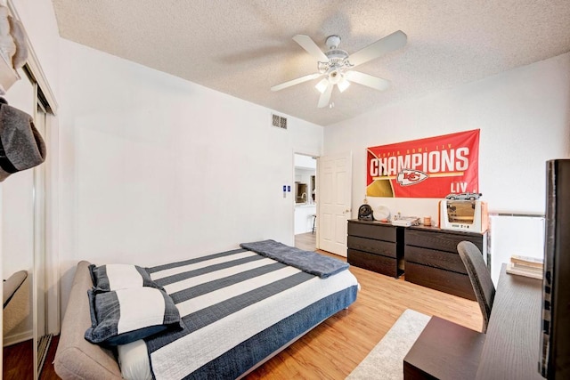 bedroom featuring visible vents, a ceiling fan, wood finished floors, and a textured ceiling