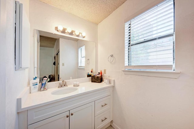 bathroom with a healthy amount of sunlight, vanity, and a textured ceiling