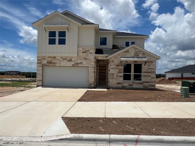 12009 Cearley Dr, Austin, TX 78758 - view of front of property featuring stone siding, an attached garage, concrete driveway, and board and batten siding