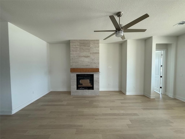 12009 Cearley Dr, Austin, TX 78758 - unfurnished living room with a textured ceiling, ceiling fan, a tiled fireplace, and light wood finished floors