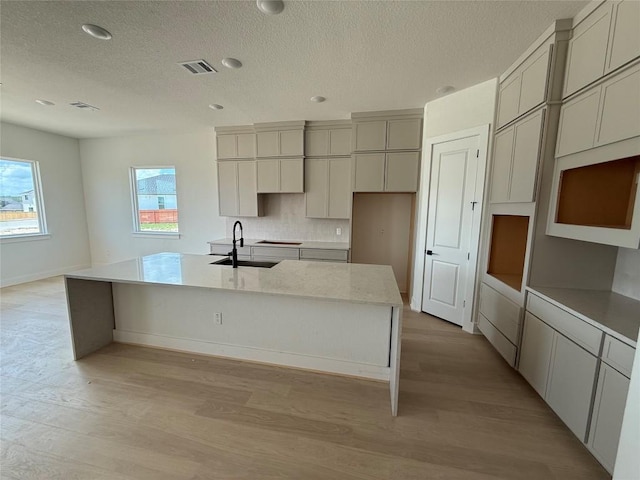 12009 Cearley Dr, Austin, TX 78758 - kitchen featuring an island with sink, light wood-type flooring, a textured ceiling, healthy amount of natural light, and recessed lighting