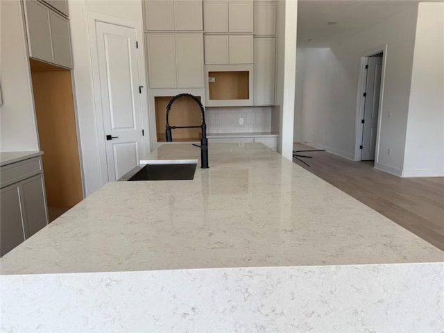 12009 Cearley Dr, Austin, TX 78758 - kitchen featuring wood finished floors, light stone countertops, and a center island with sink