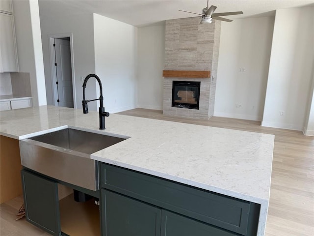 12009 Cearley Dr, Austin, TX 78758 - kitchen featuring a ceiling fan, open floor plan, a fireplace, light stone countertops, and light wood finished floors