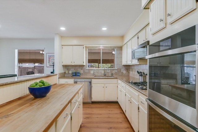 7809 Taranto Dr, Austin, TX 78729 - kitchen featuring appliances with stainless steel finishes, decorative backsplash, healthy amount of natural light, light wood-type flooring, and recessed lighting