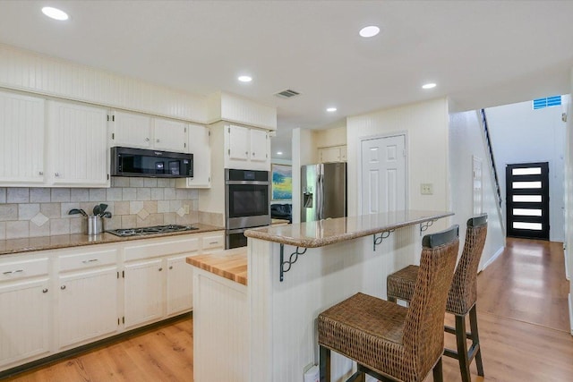7809 Taranto Dr, Austin, TX 78729 - kitchen with appliances with stainless steel finishes, light wood-style flooring, backsplash, a center island, and recessed lighting