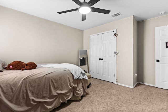 bedroom with a closet, baseboards, light carpet, visible vents, and ceiling fan