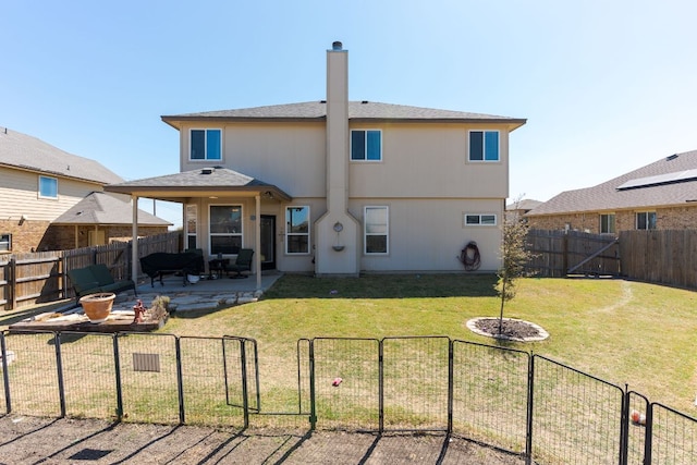 back of house with a patio, a chimney, a fenced backyard, and a lawn