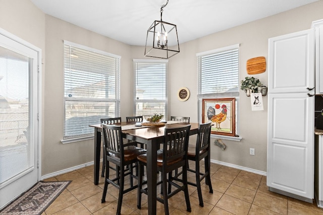 dining area with light tile patterned floors, baseboards, and a notable chandelier