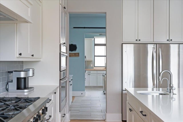 821 S Angel Light Dr, Spicewood, TX 78669 - kitchen featuring light countertops, stainless steel appliances, decorative backsplash, a sink, and white cabinets