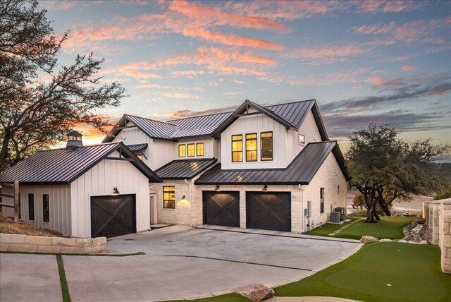 821 S Angel Light Dr, Spicewood, TX 78669 - modern farmhouse with a standing seam roof, a putting area, a metal roof, a garage, and driveway