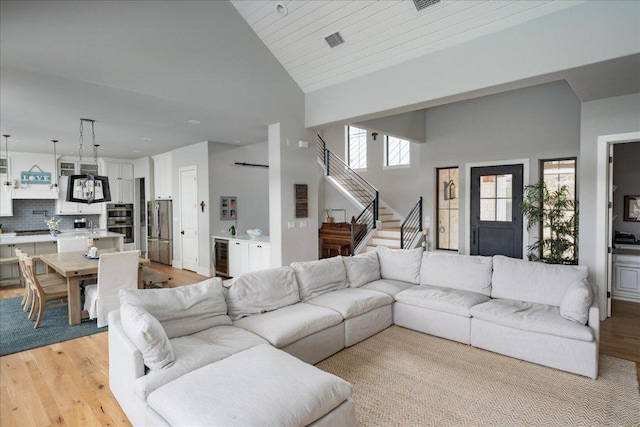 821 S Angel Light Dr, Spicewood, TX 78669 - living room with light wood-style floors, stairs, high vaulted ceiling, and beverage cooler
