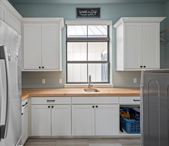 821 S Angel Light Dr, Spicewood, TX 78669 - kitchen featuring freestanding refrigerator, wooden counters, white cabinetry, and washer / clothes dryer