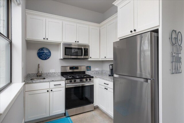 821 S Angel Light Dr, Spicewood, TX 78669 - kitchen featuring stainless steel appliances, white cabinets, and light stone countertops