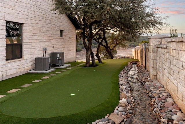 821 S Angel Light Dr, Spicewood, TX 78669 - yard at dusk with an area to practice putting and cooling unit