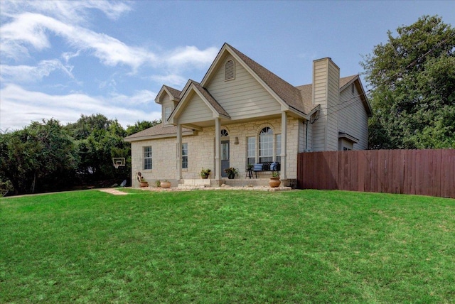 back of house with a yard, stone siding, fence, and a chimney