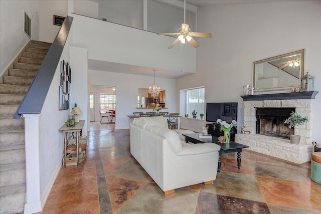living room featuring visible vents, a stone fireplace, ceiling fan with notable chandelier, stairs, and high vaulted ceiling