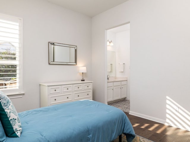 1491 Hazy Hills Loop, Dripping Springs, TX 78620 - bedroom featuring ensuite bathroom, a sink, dark wood-style floors, and baseboards
