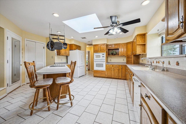 59 Fairview Dr, Round Rock, TX 78665 - kitchen featuring open shelves, white appliances, a skylight, ceiling fan, and a breakfast bar