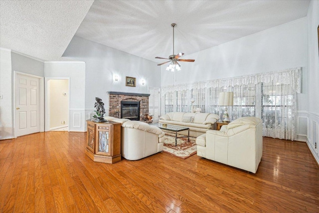 59 Fairview Dr, Round Rock, TX 78665 - living room featuring wood finished floors, a decorative wall, ceiling fan, a towering ceiling, and a fireplace