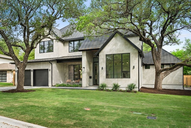 view of front of house with stucco siding, an attached garage, a front lawn, a standing seam roof, and metal roof