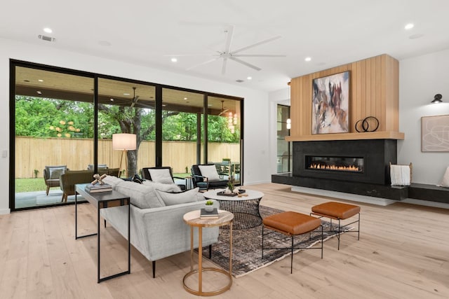 living room featuring wood finished floors, ceiling fan, a fireplace, and recessed lighting