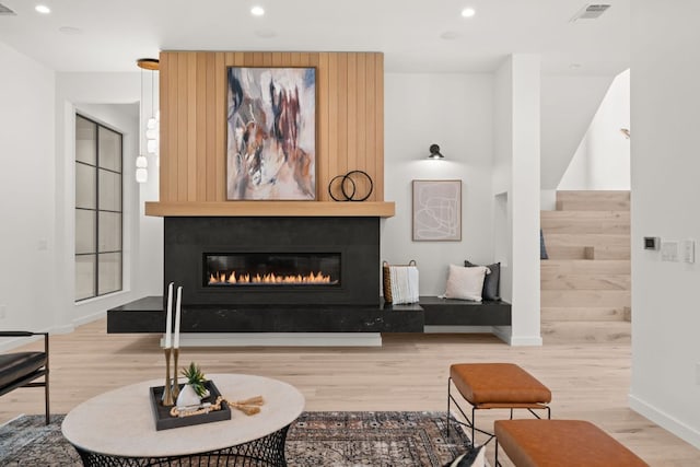 living area featuring baseboards, recessed lighting, a fireplace, visible vents, and wood finished floors