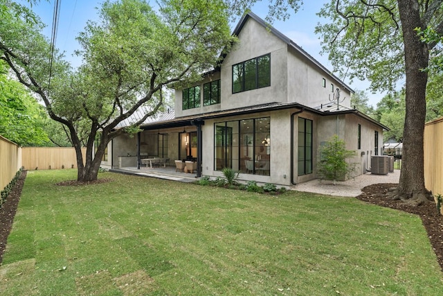 rear view of house with a patio, stucco siding, a fenced backyard, central AC, and a lawn