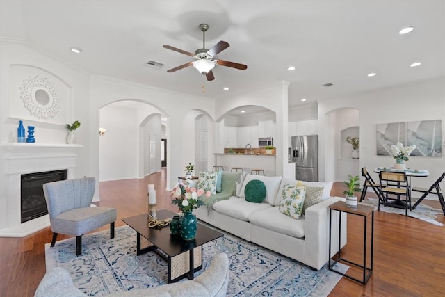 2529 Mirasol Loop, Round Rock, TX 78681 - living room with ceiling fan, arched walkways, wood finished floors, recessed lighting, and a glass covered fireplace