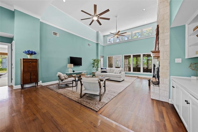 living room with ceiling fan, a towering ceiling, dark wood finished floors, and visible vents