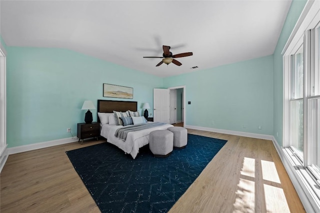 bedroom with visible vents, baseboards, a ceiling fan, and wood finished floors
