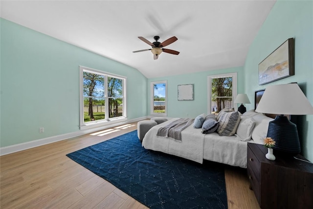 bedroom with baseboards, multiple windows, wood finished floors, and lofted ceiling