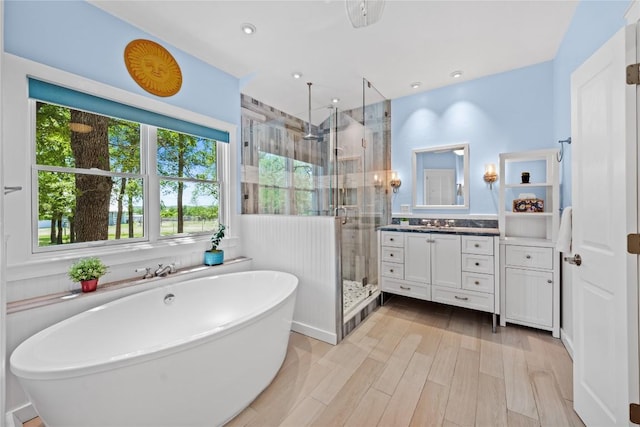 full bathroom with a soaking tub, a shower stall, vanity, recessed lighting, and wood finished floors