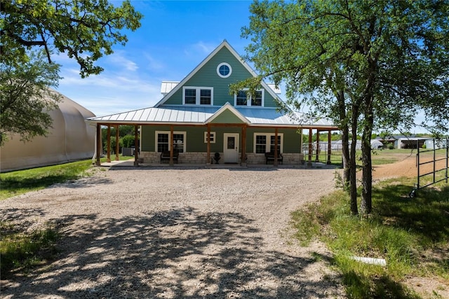 view of front facade with driveway, stone siding, metal roof, and a standing seam roof