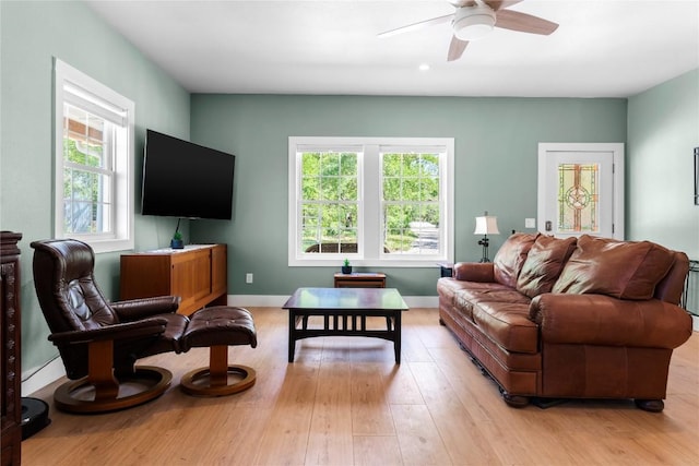 living area featuring light wood-style flooring, ceiling fan, and baseboards