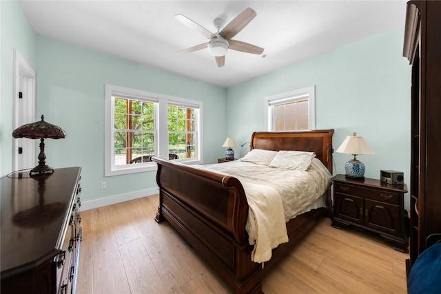 bedroom with light wood finished floors, baseboards, and a ceiling fan