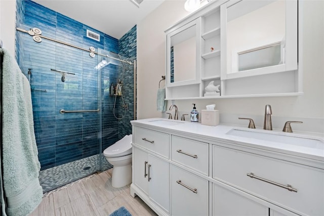 bathroom featuring double vanity, a stall shower, a sink, and toilet