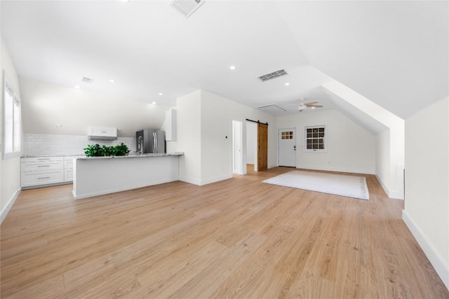 interior space with light wood-style floors, a barn door, visible vents, and baseboards