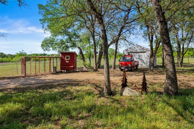 view of yard featuring an outbuilding, dirt driveway, fence, and a garage