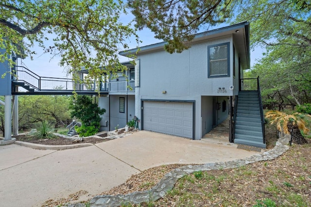 view of front of home featuring stairway, an attached garage, concrete driveway, and stucco siding
