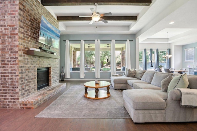 living room featuring a fireplace, a raised ceiling, wood finished floors, and ceiling fan